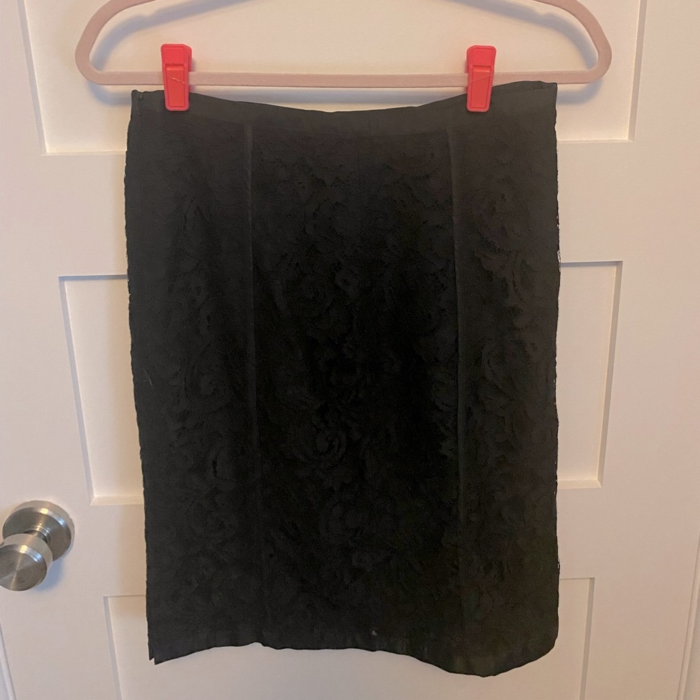Black lace pencil skirt. Lined, with small side slit and trimmed ribbon detail.